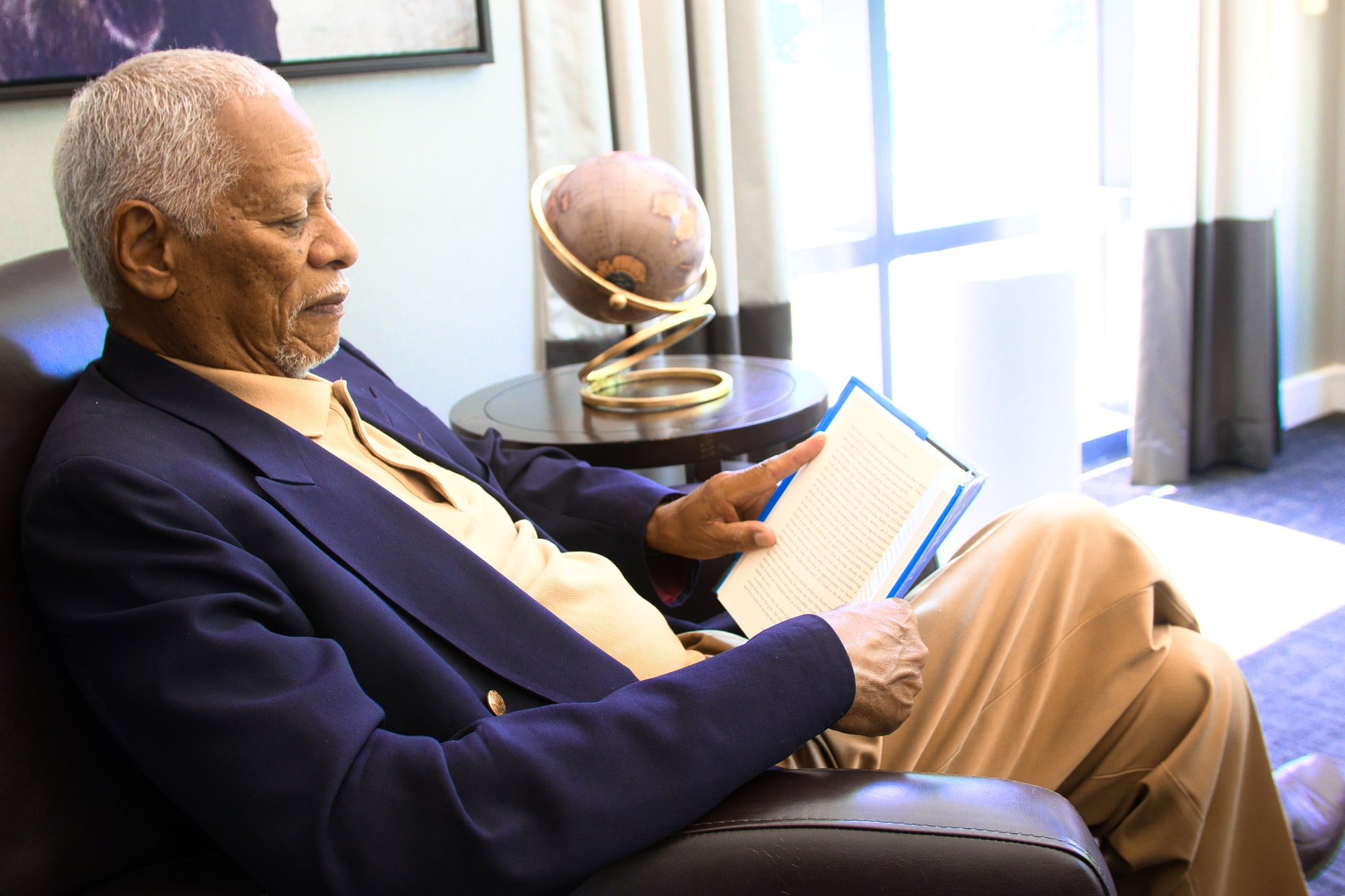 Gentleman reading a book in the retirement residence library