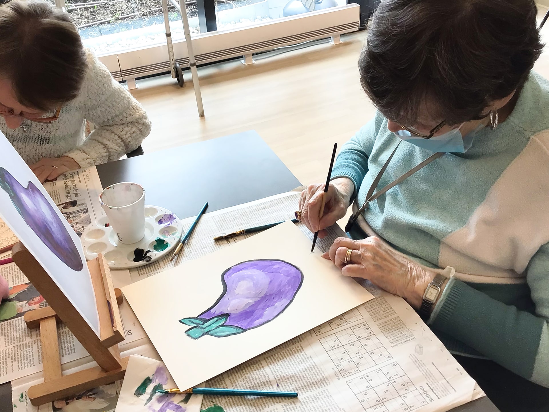 Elderly woman painting an eggplant with water colours